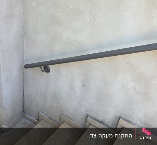 מעקה אחיזה ממתכת מותקן על קיר לאורך גרם מדרגות